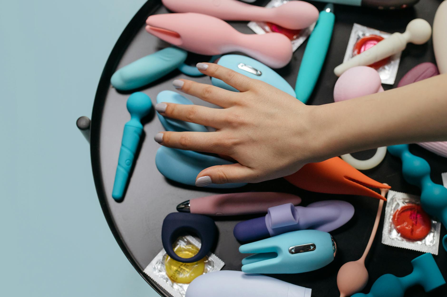 Hands holding pastel-colored silicone sex toys including lemon clitoral vibrators