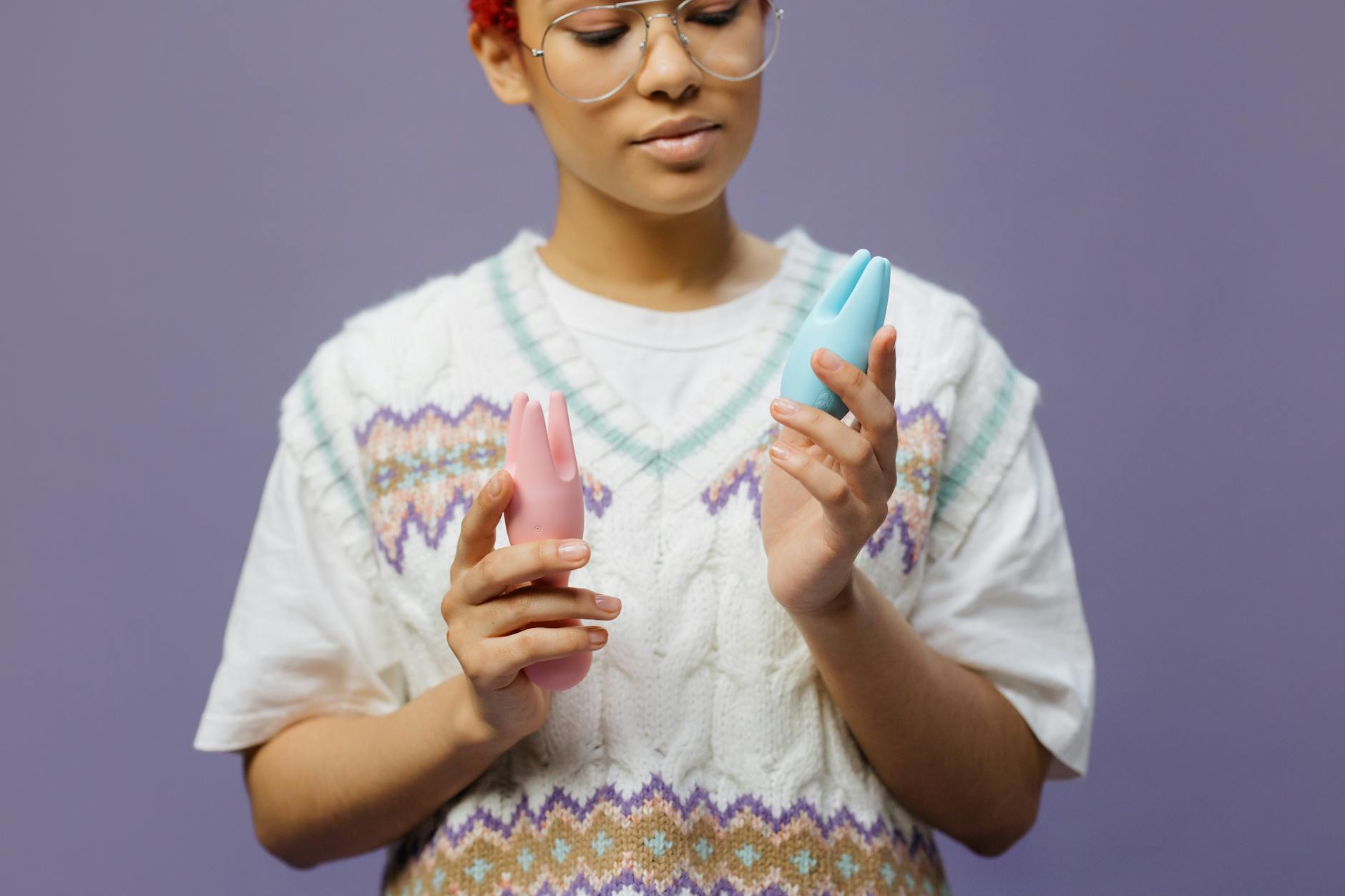 Woman holding a blue and pink silicone vibrator, contemplating pleasure and sensation.